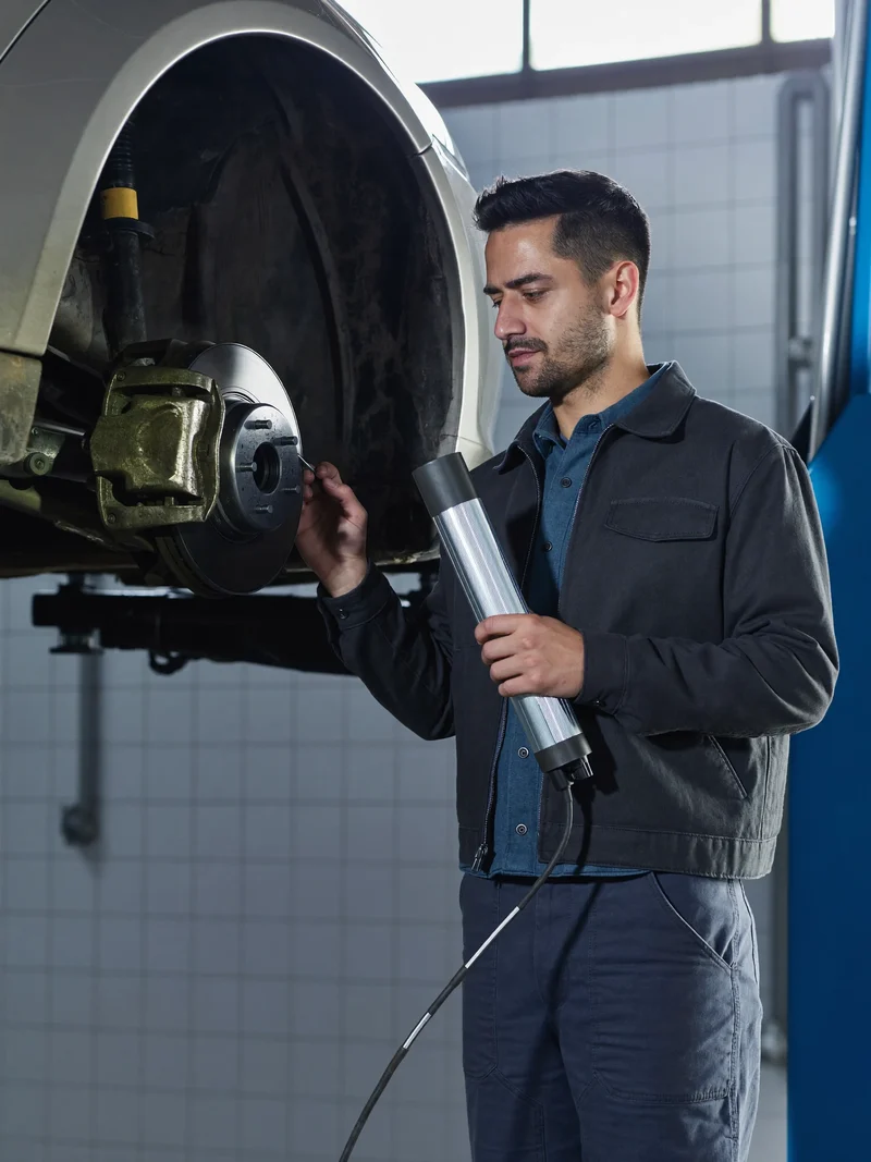 Mechanik svítilnou kontroluje brzdový kotouč a třmen na zvednutém voze